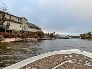 Photo from the viewpoint of a boat bow showing water and houses on the waterfront.