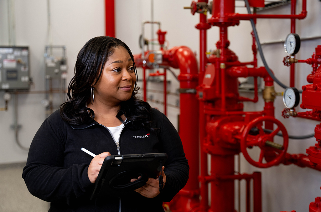 A woman with a tablet and pen examines piping with sensors on it