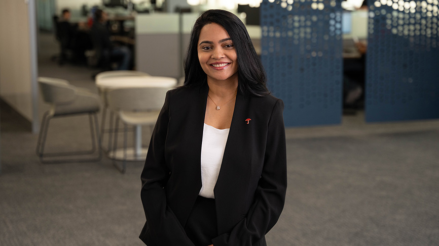 Smiling woman in business attire standing in a modern office.