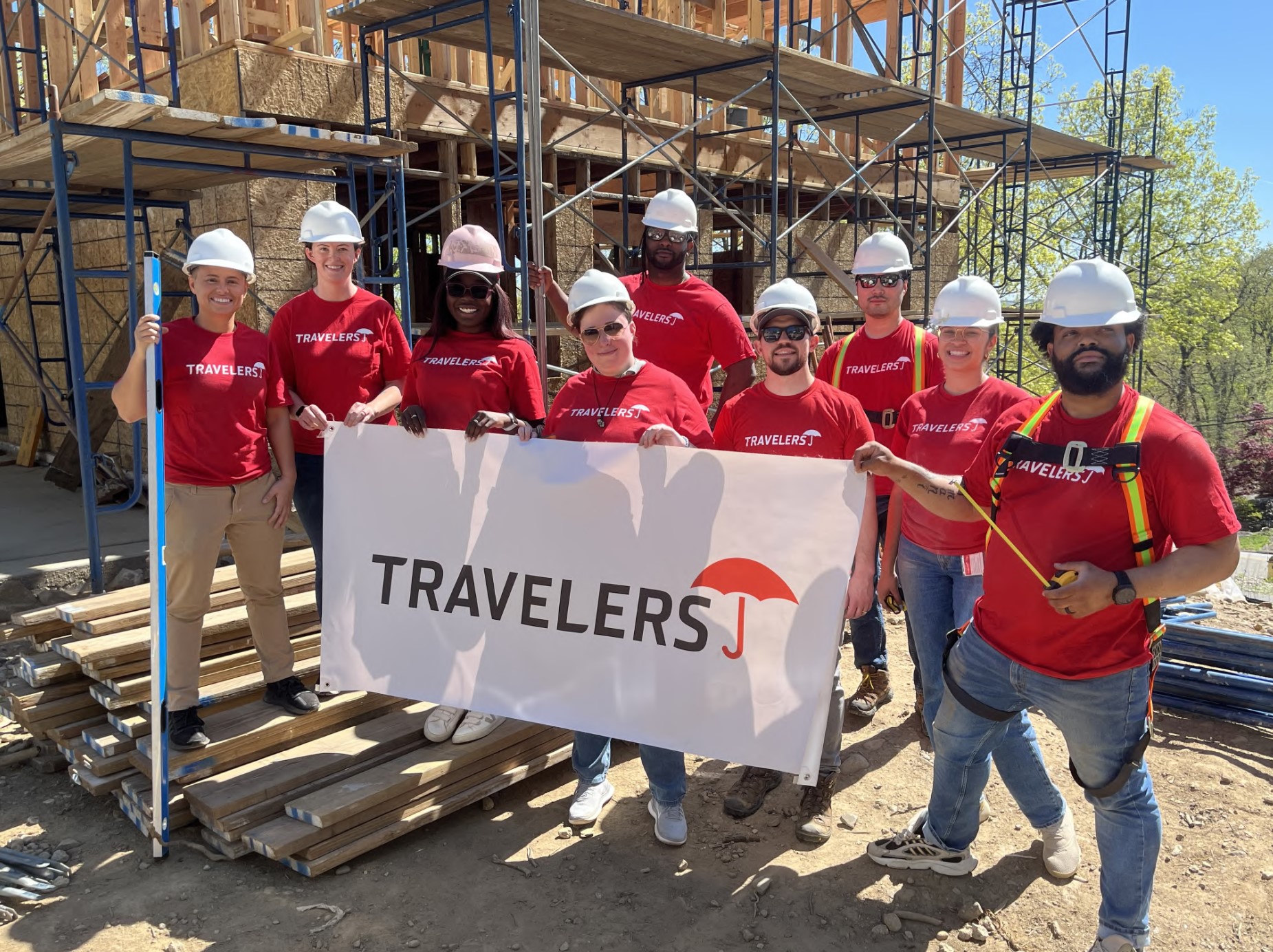 Travelers employees in hard hats volunteering at a construction site.