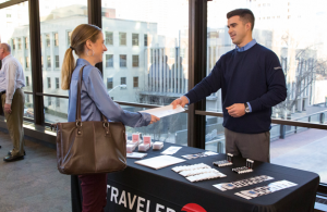 Travelers’ recruiter hands career information to a job seeker at a hiring event