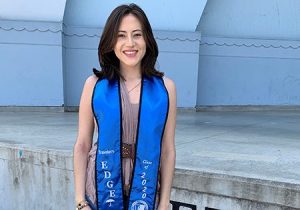 Diana Sanchez standing and smiling wearing a Travelers EDGE graduation sash.