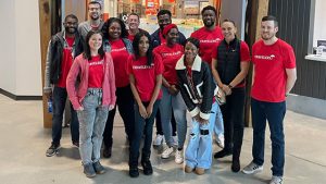 A group of Travelers employees in red Travelers shirts smiles for the camera at a Junior Achievement volunteer event.