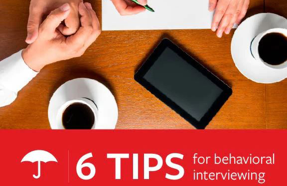 Two people at a table with coffee, a tablet, and a notepad during an interview. Text reads: “6 Tips for behavioral interviewing” alongside the Travelers umbrella logo.