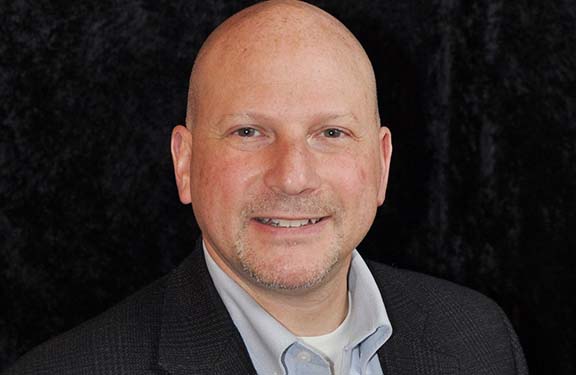 Stephen Brand, a Travelers employee, featured in a professional headshot, representing leadership and expertise at Travelers.