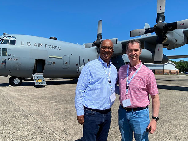 Two Travelers leaders on a flight line on front of a cargo plane.