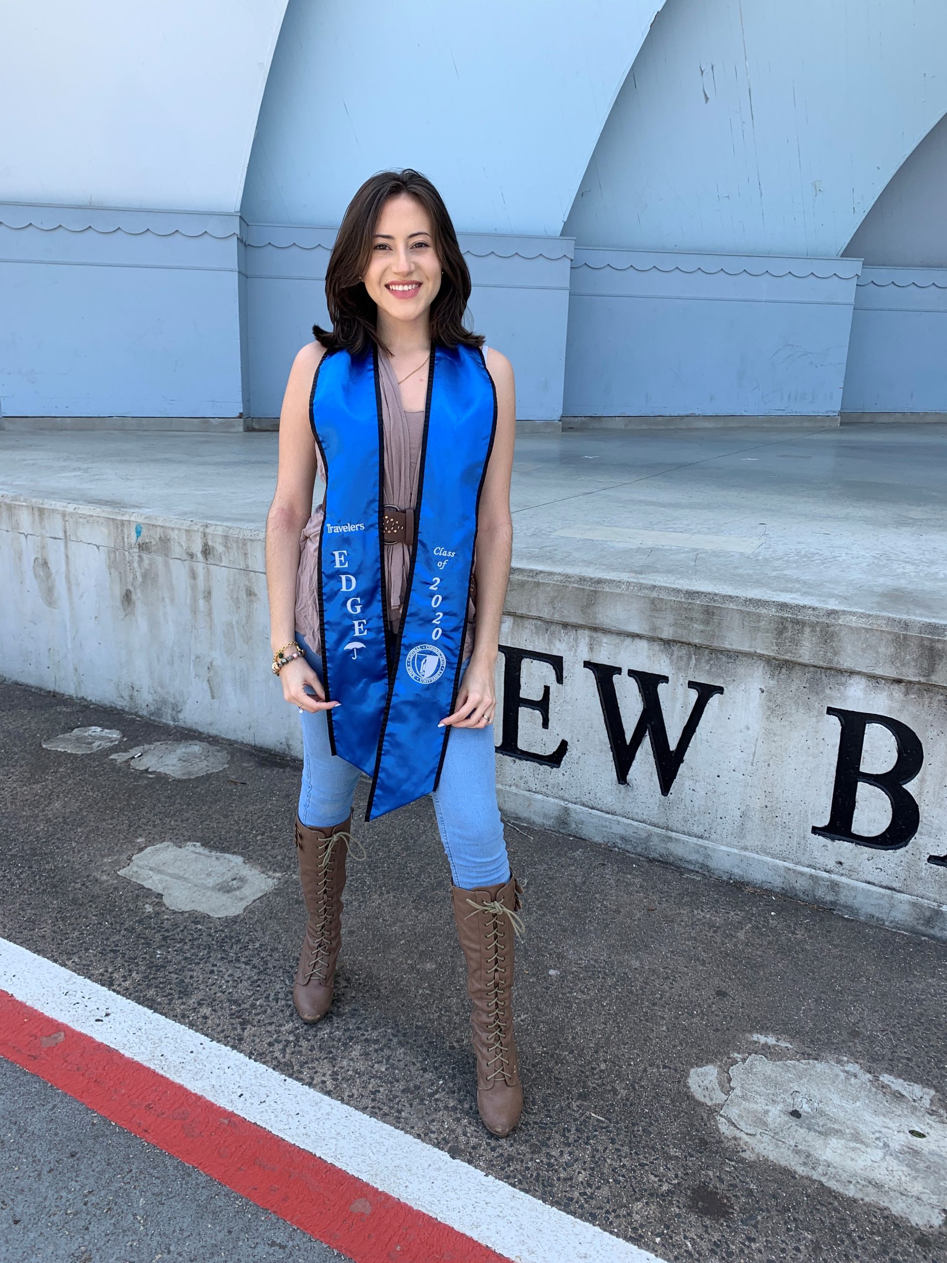 Diana Sanchez standing and smiling wearing a Travelers EDGE graduation sash.